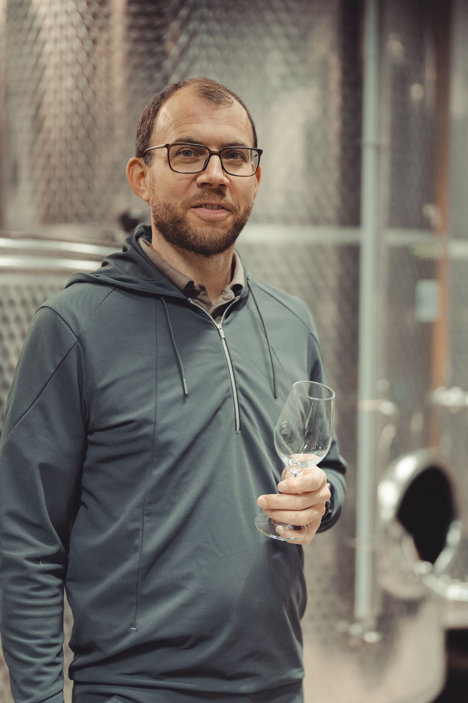 Andreas Holzer mit einem Weinglas im Keller des Weinguts